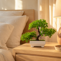 Mini artificial bonsai plant on a bedside table in a warm bedroom